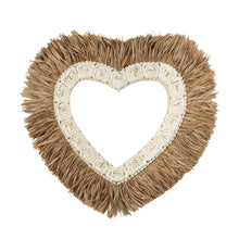 Heart-shaped decorative item with beige fringe and white floral center on a white background